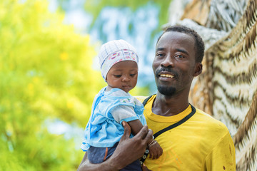 Happy African black father holding his little baby outdoors.Copy space