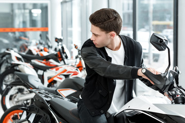 Ready for road trips. Young male customer sitting on a new motorbike looking over his shoulder at the motorcycle salon