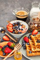 Breakfast table with cereal granola, milk, fresh berries, coffee and waffles