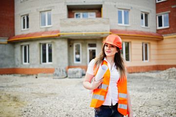 Engineer builder woman in uniform waistcoat and orange protective helmet hold business paper...