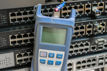 Optical Time Domain Reflectometer with wire connected to it is on the background of several switches