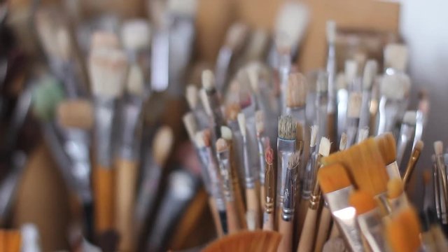A large assortment of art brushes for drawing with paints. Brushes made of natural and boring fur stand in the stand. Ponoramnaya shooting. close-up. macro.