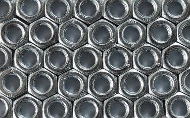 Background of identical nuts with thread. Metal texture.