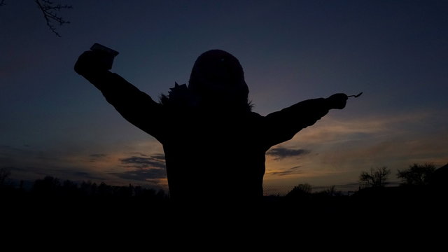 six year girl raised her hands up with a jar of yogurt and a spoon at sunset