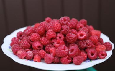Red fresh ruspberry on the  plate  in  the  garden  in  the summer 