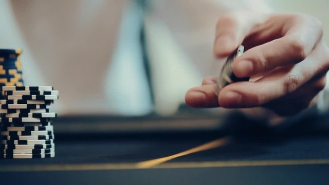 Casino: Man playing poker, excited, turns casino tokens in hand. Close up slow motion
