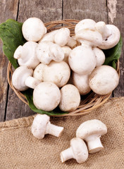 Basket with fresh champions on an old wooden background