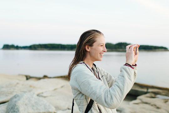 Young woman taking pictures in harbor, Rockland Maine