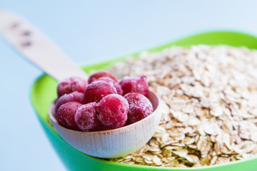 Berries in a wooden spoon on the background, plate with cereal