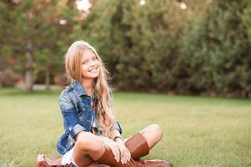 Smiling teenage girl 14 -16 year old wearing stylish clothes in park. Looking at camera. Posing...