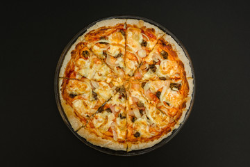 Homemade pizza on a black background.