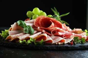 Food tray with delicious salami, pieces of sliced ham, sausage, tomatoes, salad and vegetable - Meat platter with selection