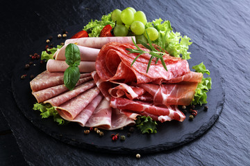 Food tray with delicious salami, pieces of sliced ham, sausage, tomatoes, salad and vegetable - Meat platter with selection