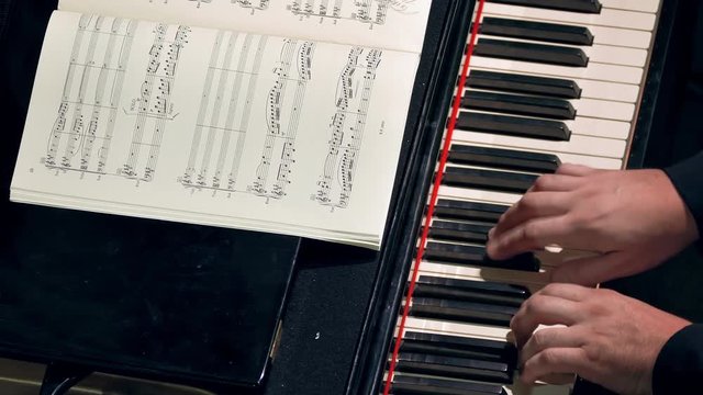 Pianist Playing / Piano Player / Orchestra Musician. Pianist plays piano at a classical music concert. Music sheets of VII century classics (now public-domain). Hands and keyboard close-up.