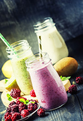 Multicolored berry and fruit smoothies, assorted in glass bottles, selective focus