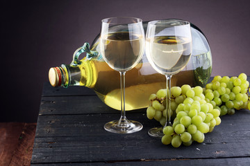 Obraz premium Bottle and glass of white wine, grape on wooden table