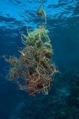Marine debris jammed fishing net drifting along coral reef Sulawesi Indonesia