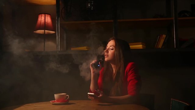 The girl in the red jacket Smoking the electronic cigarette and talking on a cell phone.