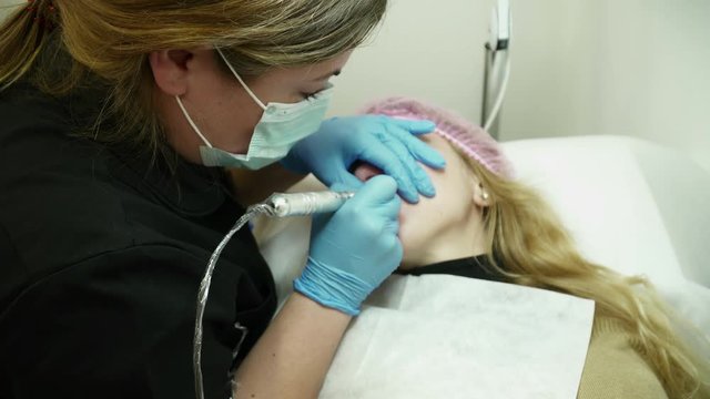 Cosmetologist is making the permanent makeup in beauty salon