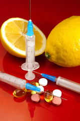 Lemons on a red background with syringes and pills. Medical preparations and vitamin C....