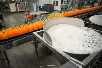 High angle view of orange cold drink bottles on production line