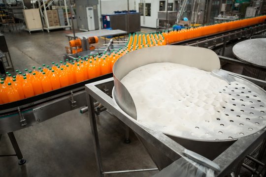 High angle view of orange cold drink bottles on production line