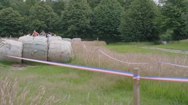  Competitors in assault course race, males helping female team members over obstacles. 