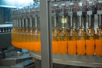 Bottles being filled with juice on production line 
