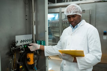 Worker holding clipboard while operating machine 