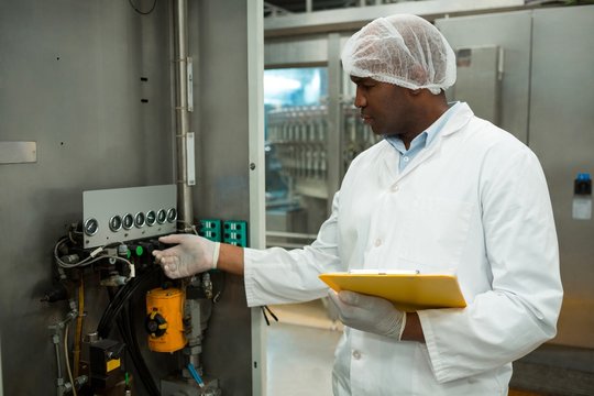 Confident worker operating machine in juice factory