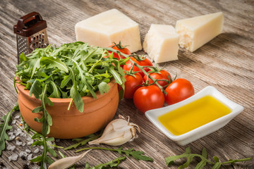 Arugula, tomatoes,cheese and oil on rustic table