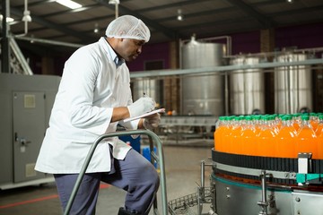 Worker checking bottles in juice factory