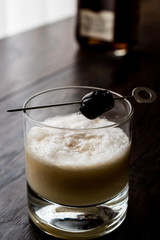 Whiskey sour cocktail served with olive.