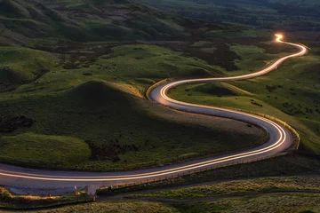 Fotobehang Winding curvy rural road with light trail from headlights leading through British countryside. © _Danoz