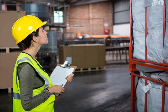 Confident female worker examining products in warehouse