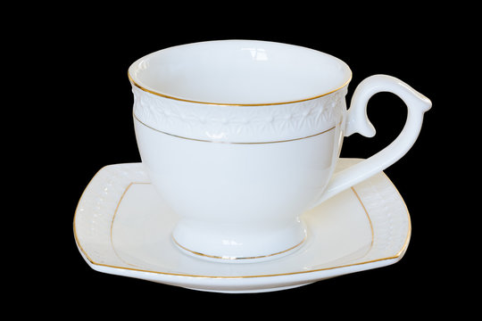 White porcelain cup with a saucer for tea or coffee, demitasse or teacup. Isolated, black background.