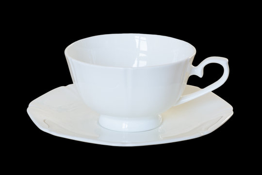 White porcelain cup with a saucer for tea or coffee, demitasse or teacup. Isolated, black background.