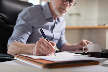 Senior businessman taking notes, hard light