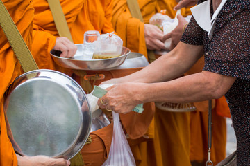 Buddhist monk of Thailand while stand in a row waiting people put rice and food offerings in their alms bowl for make merit