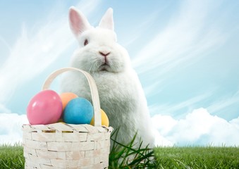 Easter rabbit with basket of eggs in front of blue sky