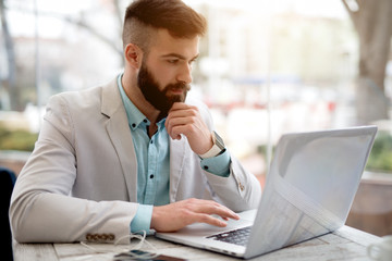 Side view of man in suit checking emails on laptop.