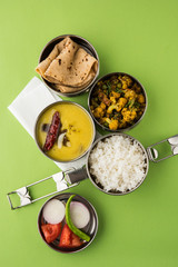 indian typical stainless steel lunch box or tiffin with north indian or maharashtrian food menu like chapati//roti, dal tadka, white rice and aloo / potato sabji / gobi or cauliflower sabji with salad © StockImageFactory