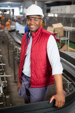 Happy male employee standing by conveyor in factory