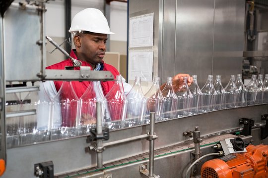 Male employee examining bottles in factory
