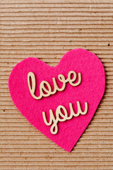 Love You - wooden words on pink heart with corrugated paper background
