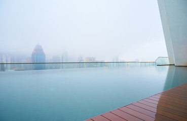 Swimming pool on roof top with beautiful city skyline view,early morning with mist ,  kuala lumpur malaysia.