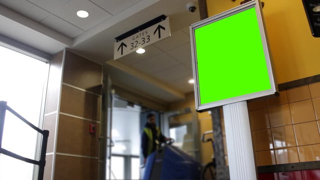 Generic green screen sign at airport terminal near gate as janitor comes by