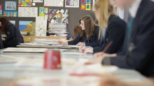  Group of teen girls in school art class, focus on 1 girl talking to her frien