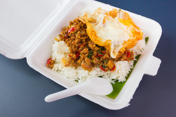 Rice topped with stir-fried pork and basil on foam box