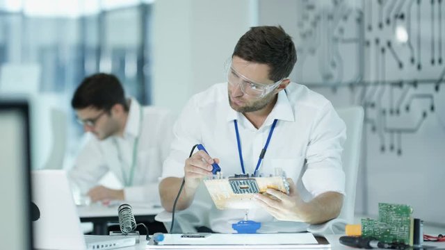  Electronics engineers working in lab building & testing electronic devices